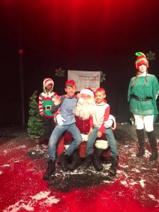 two boys posing for photo with santa at glowing hearts community give and get